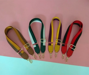Detail of adjustable cotton bag straps with colorful stripes and gold metal buckles