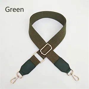 Détail d'une bandoulière en toile verte réglable avec crochets dorés et renforts en cuir