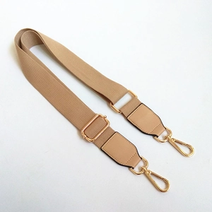 Détail de la bandoulière en toile beige avec bouts en cuir et fermoirs dorés brillants