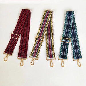 Close-up of three colorful woven bag straps with golden metal hooks and buckles