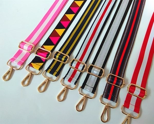 Detail of adjustable nylon bag straps with colorful stripes and gold metal buckles