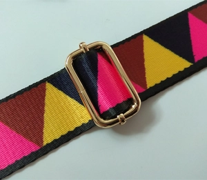 Detail of colorful geometric nylon bag strap with polished gold metal buckle adjuster