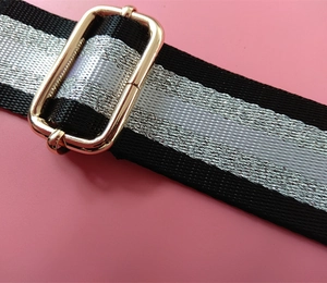 Detail of adjustable black and silver striped nylon bag strap with gold metal buckle