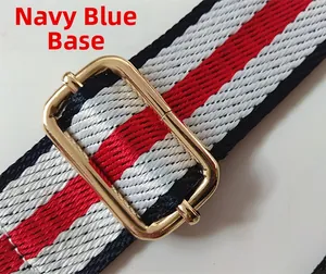 Detail of red and navy blue striped nylon bag strap with polished gold metal buckle