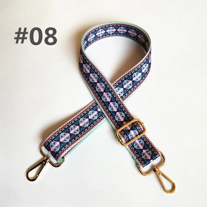 Detail of adjustable wide shoulder strap with ethnic patterns and gold metal swivel hooks
