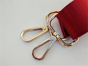 Close-up of golden metal lobster clasps and thick wine red nylon webbing for straps