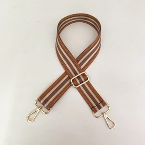 Détail d'une bandoulière tissée réglable avec rayures classiques et boucles en métal doré