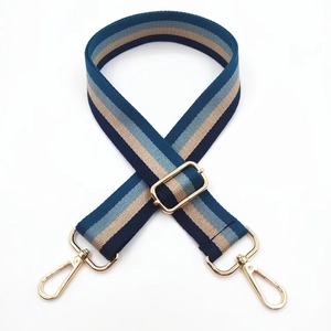 Detail of adjustable blue and beige striped fabric bag strap with gold metal hooks
