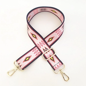 Detail of pink ethnic geometric pattern bag strap with gold metal hooks and buckle
