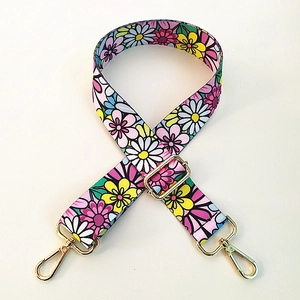 Detail view of floral print shoulder strap with golden metal hooks and buckles