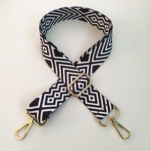 Close-up of geometric ethnic pattern bag strap with gold metal buckles and adjuster