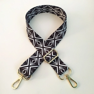 Detail of wide geometric strap with gold metal hooks and adjustable buckle for bags