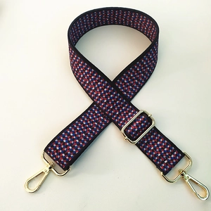 Detail of red white and blue woven bag strap with adjustable gold lobster claw clasps