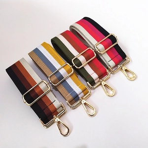 Close-up of adjustable striped canvas shoulder straps with polished light gold metal buckles