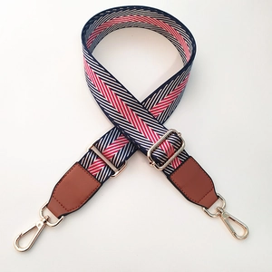 Close-up of adjustable nylon strap with red, blue, and white chevron pattern and gold clips