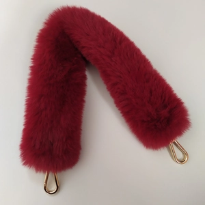 Close-up of fluffy burgundy faux fur handbag strap with gold metal lobster clasps