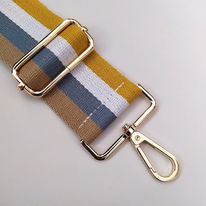 Detail of colorful striped canvas bag strap with polished light gold metal buckles