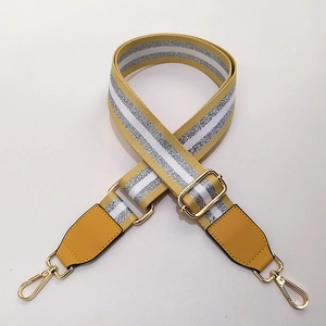 Détail de la bandoulière jaune réglable avec rayures argentées et crochets dorés