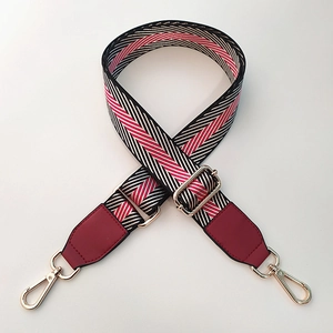 Detail of adjustable nylon strap with pink herringbone pattern and gold metal buckles
