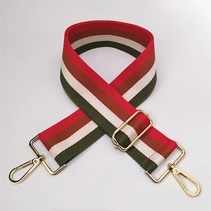 Detail of adjustable wide striped cotton shoulder strap with golden metal snap hooks