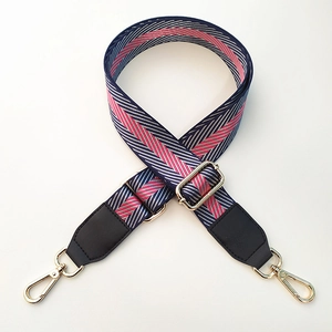 Close-up of a striped nylon bag strap with high-density weave and gold metal hooks