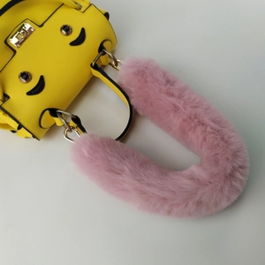 Close-up of pink faux fur handle strap on a yellow handbag with iconic eye hardware