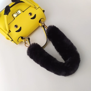 Close-up of fluffy black faux fur handle on bright yellow bag with smile detail