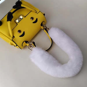 Detail of yellow bag with cartoon smiley face and fluffy white faux fur handle cover
