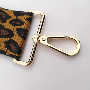 Detailed close-up of leopard print woven strap with gold rotating metal lobster clasp