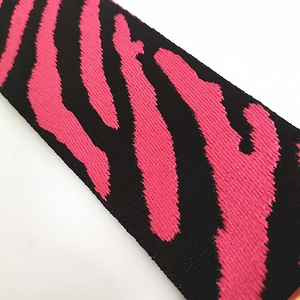 Gros plan sur la sangle brodée zèbre rouge rose et noir avec une texture tissée épaisse