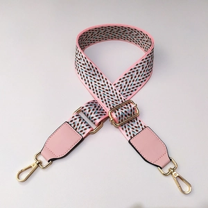 Détail de la bandoulière large tissée ajustable avec embouts en cuir rose et boucles dorées