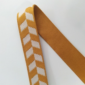 Macro detail of mustard yellow jacquard woven strap with white geometric arrow pattern
