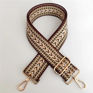 Detail of colorful geometric jacquard shoulder strap with golden metal lobster clasps