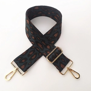 Close-up of leopard print woven bag strap with adjustable buckle and gold metal hooks
