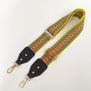 Detailed close-up of ethnic geometric embroidered bag strap with golden metal lobster clasps