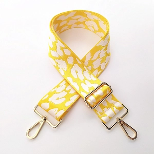 Close-up of leopard pattern wide bag strap with golden metal lobster clasps and buckles