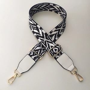 Close-up of geometric ethnic pattern bag strap with gold metal hooks and leather ends