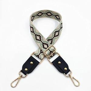 Detail of adjustable ethnic canvas bag strap with green geometric embroidery and gold hardware