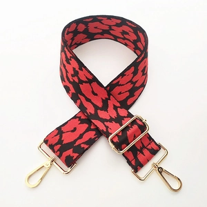 Detail of wide red and black leopard print bag strap with golden lobster clasps