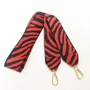 Dettaglio tracolla larga in nylon zebrato rosso e nero con moschettoni in metallo dorato