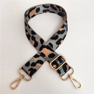 Close-up of leopard print nylon bag strap with golden metal swivel hooks and buckle