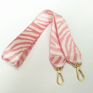 Dettaglio della tracolla rosa e bianca con motivo zebra e ganci dorati lucidi