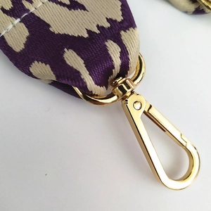 Detail of purple and beige animal print woven bag strap with polished gold buckle