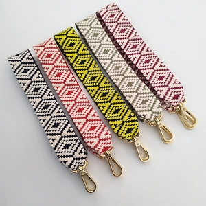 Detail of colorful woven handbag straps with geometric patterns and gold metal lobster clasps