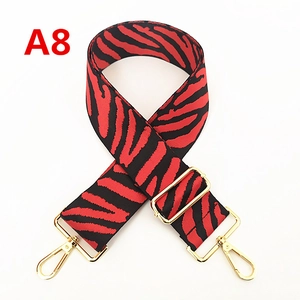 Détail de la bandoulière zébrée rouge et noire avec crochets en métal doré poli