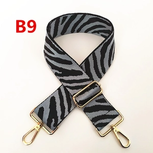 Détail d'une large bandoulière zébrée avec boucles dorées et accessoires métalliques réglables