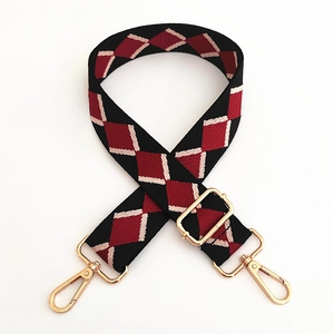 Detail of adjustable canvas bag strap with red diamond embroidery and gold metal hooks