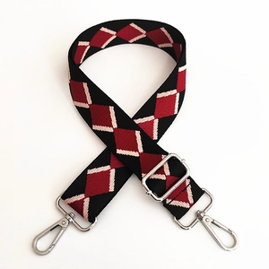 Close-up of ethnic style wide canvas strap with red and black argyle pattern and silver hooks