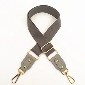 Detail view of gray canvas strap with golden metal swivel hooks and faux leather connectors