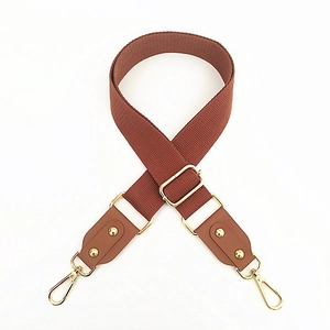 Detail of adjustable brown woven cotton strap with gold metal buckles and leather ends